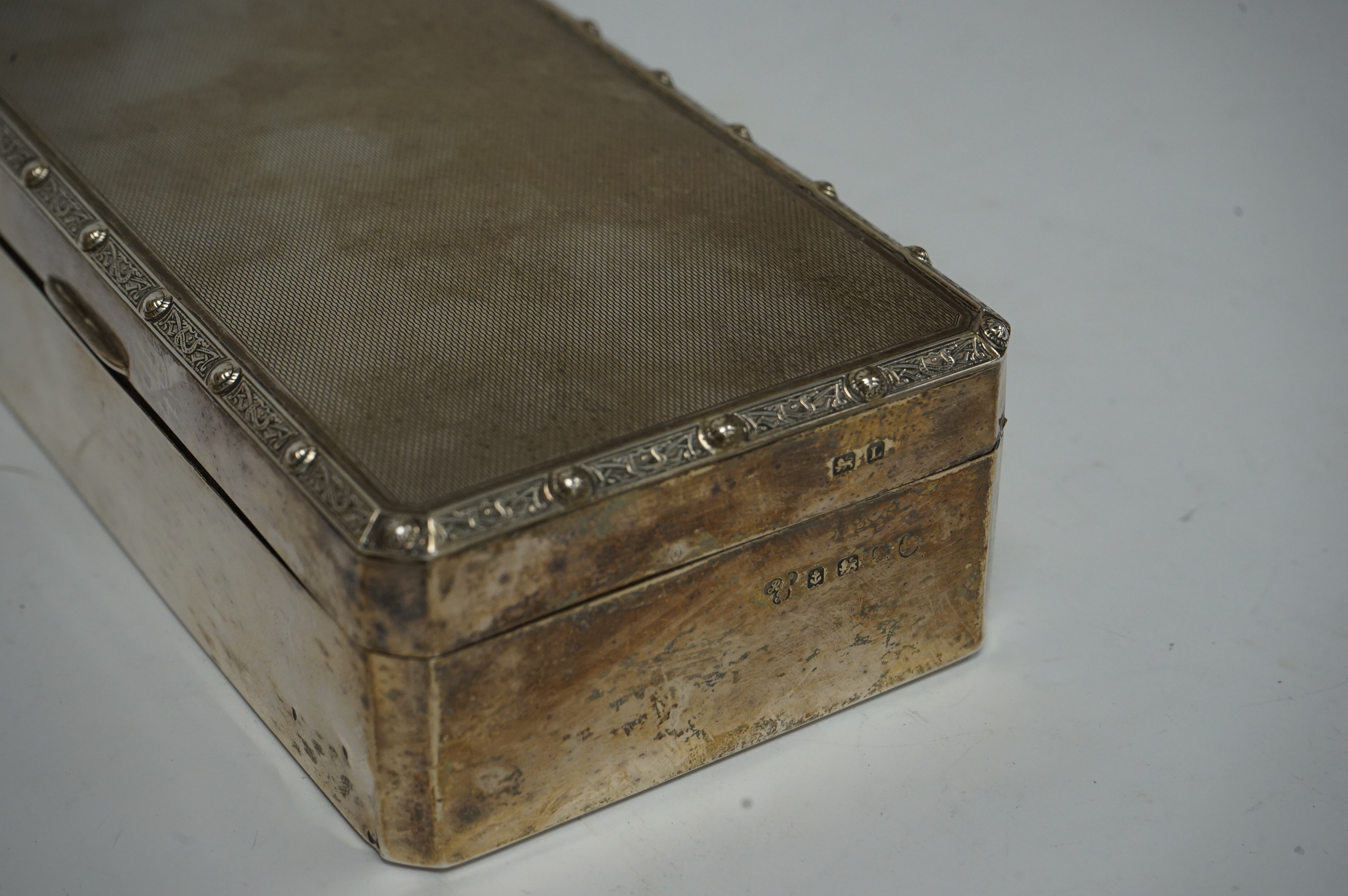 A George V silver mounted rectangular cigarette box, by Harrods Ltd, Birmingham, 1935, 16.6cm. Condition - poor to fair